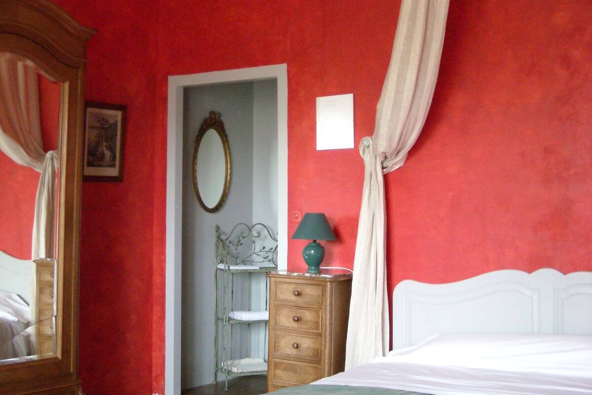 Une chambre à coucher comprenant un lit, une table de chevet, une commode, un miroir et un lustre.