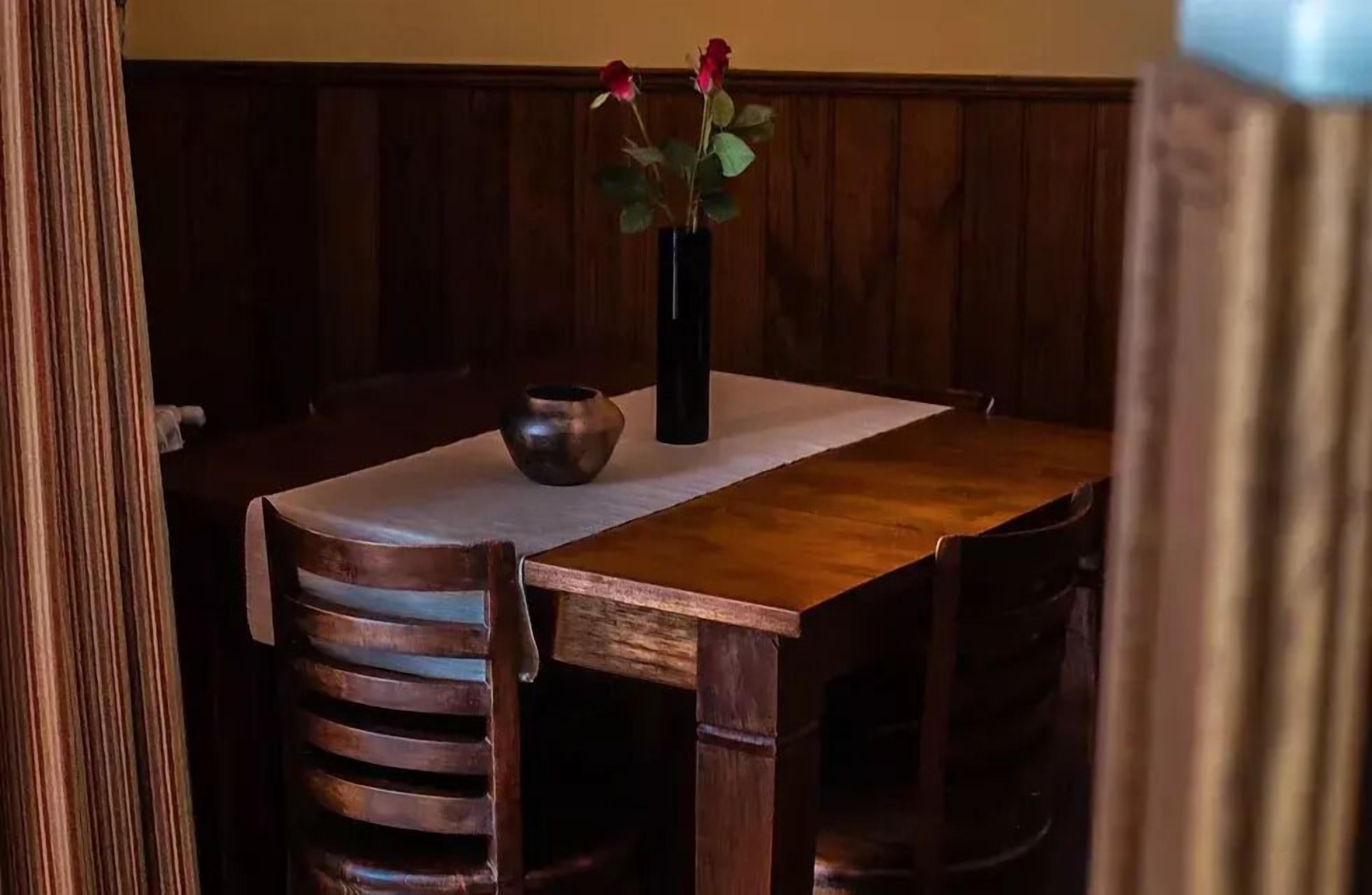 A wooden dining table with a vase of flowers and a bowl.