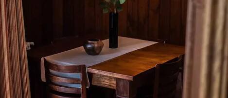 A wooden dining table with a vase of flowers and a bowl.