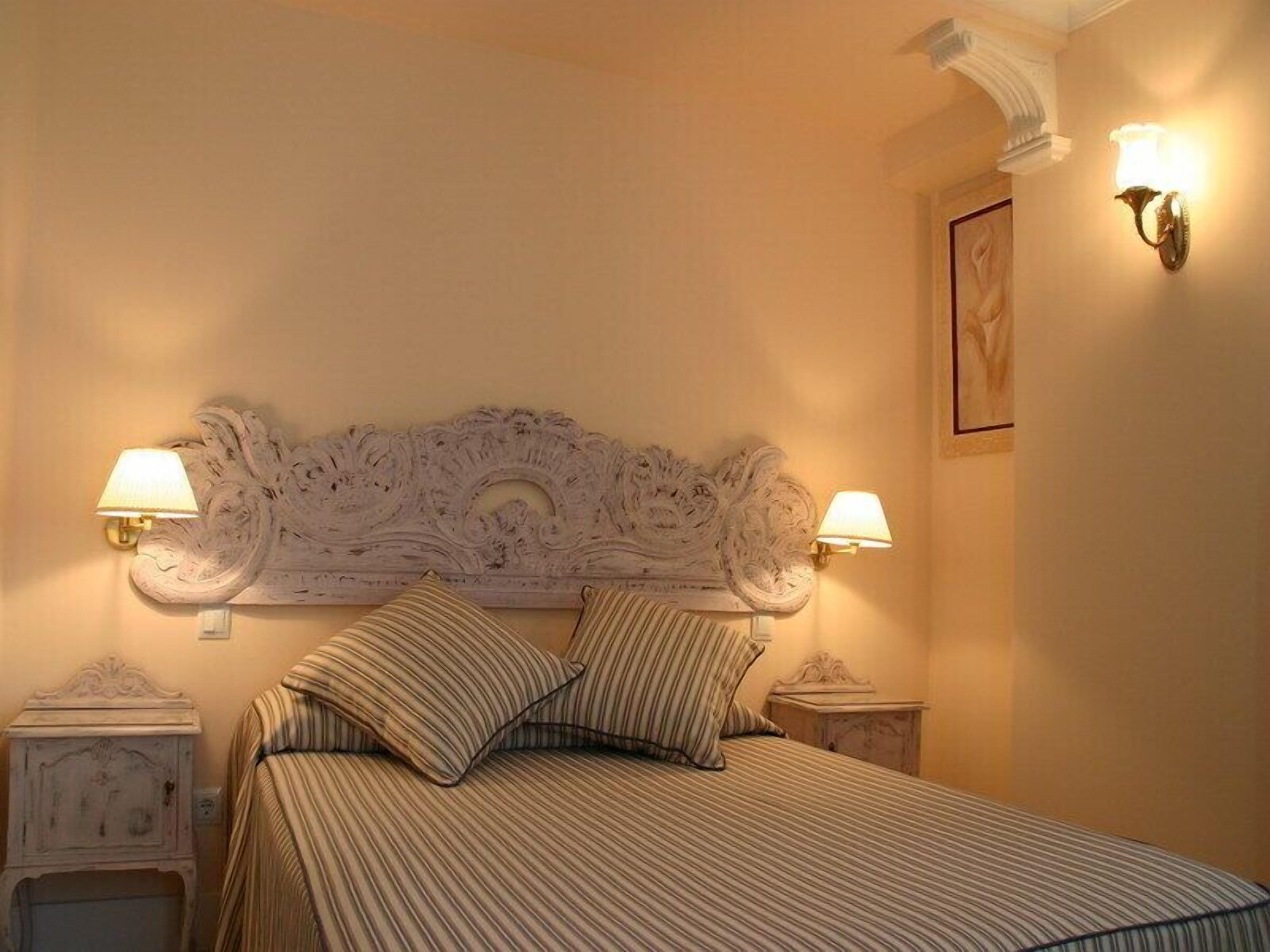 A hotel room with a large bed, two bedside tables, and a decorative headboard.