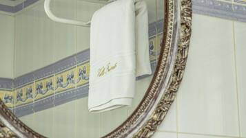 A bathroom with a white towel hanging on a rack, a decorative mirror, and patterned tiles.