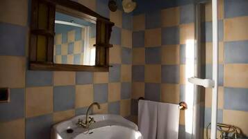 Een badkamer met een betegelde muur in ruitpatroon, een witte wastafel, een spiegel en een handdoekhouder.