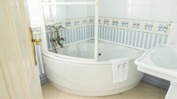 Un baño con bañera vidriada, lavamanos blanco y paredes con baldosas a rayas.
