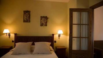 Une chambre d’hôtel avec un lit en bois, deux lampes fixées au mur et une porte avec une fenêtre.