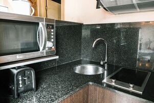 Una cocina equipada con microondas, tostadora, pileta y cocina por inducción.