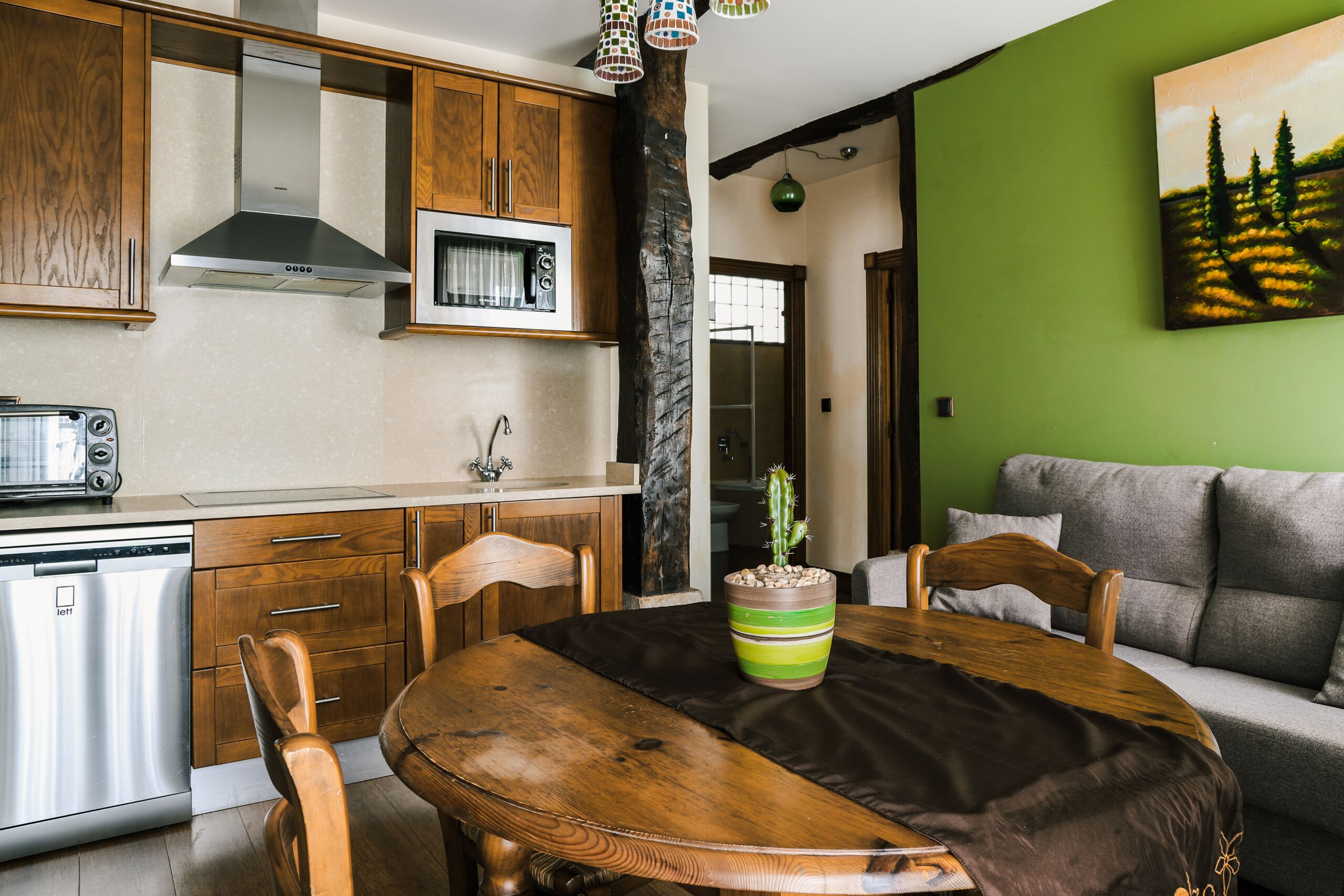 A modern kitchen with wooden cabinets, a stainless steel dishwasher, and a dining area with a wooden table and chairs.