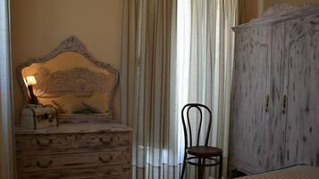 Een slaapkamer met een houten dressoir, een stoel, een bed met streepjesbeddengoed en een grote kledingkast.