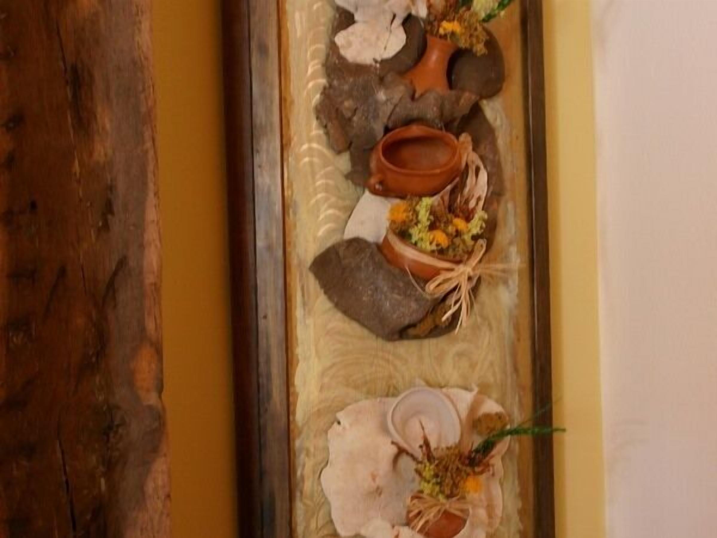Una mesa de madera con cubierta de vidrio, decorada con cerámica y flores.