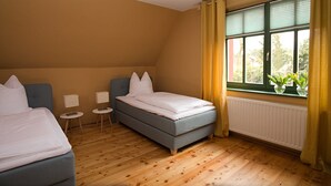 Ein Schlafzimmer mit zwei Betten, einem kleinen Tisch und einem Fenster mit Vorhängen.