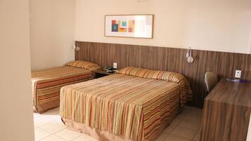 Habitación de hotel con dos camas individuales, un escritorio y una silla.