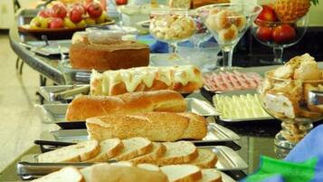Ein reichhaltiges Buffet mit verschiedenen Speisen, darunter Brot, Gebäck und Obst.