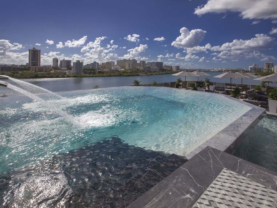 Una piscina al aire libre, camas de piscina con cargo, sombrillas