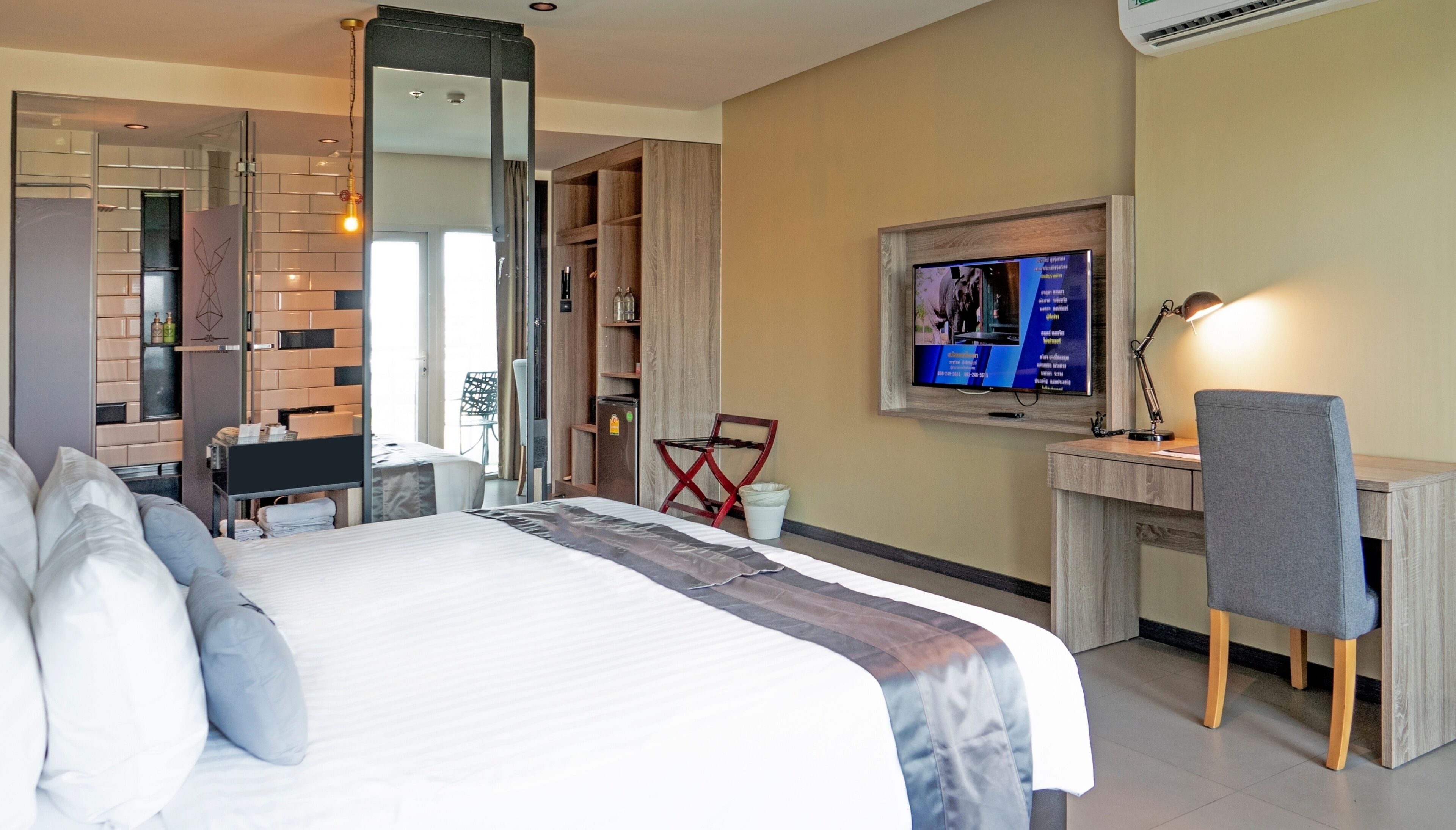 Hotellihuone, jossa on suuri sänky, työpöytä, jossa on tietokone, televisio ja tuoli.
