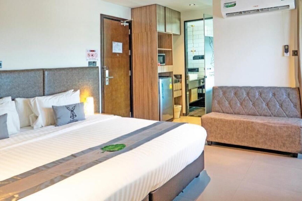 A hotel room with a bed, a sofa, a wardrobe, and a kitchenette.