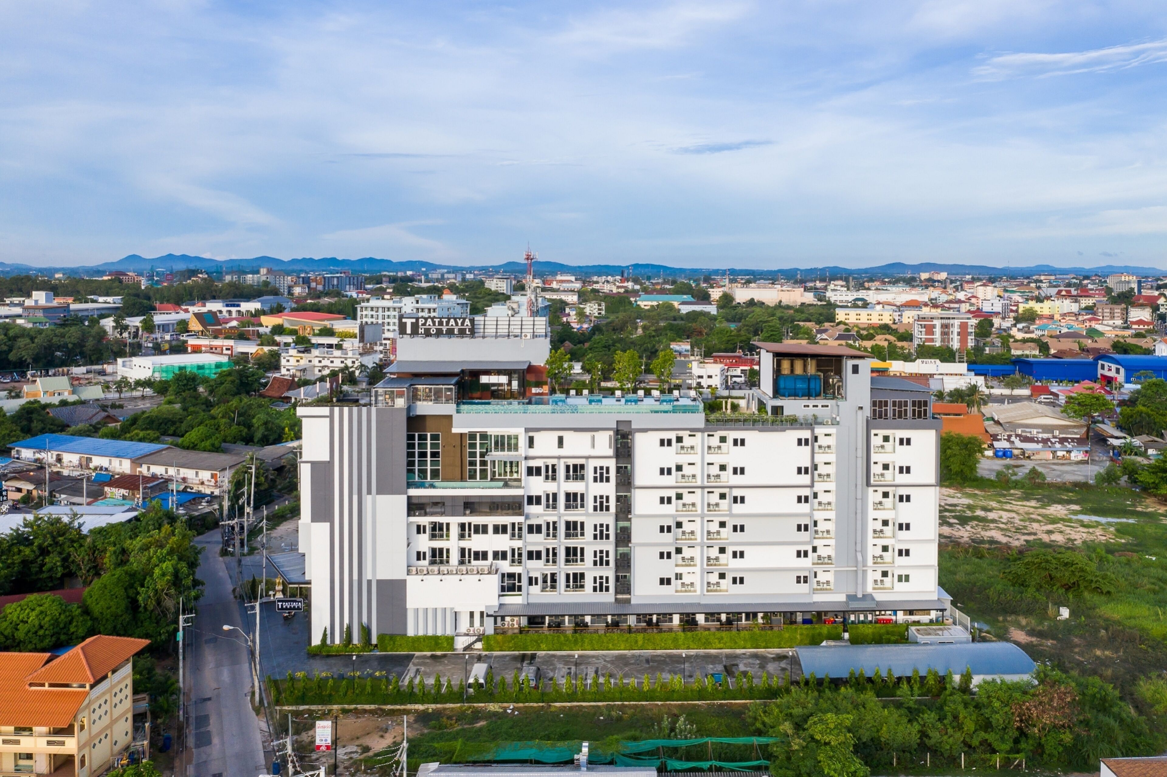 A multi-story hotel with a modern design, featuring balconies and a rooftop terrace.