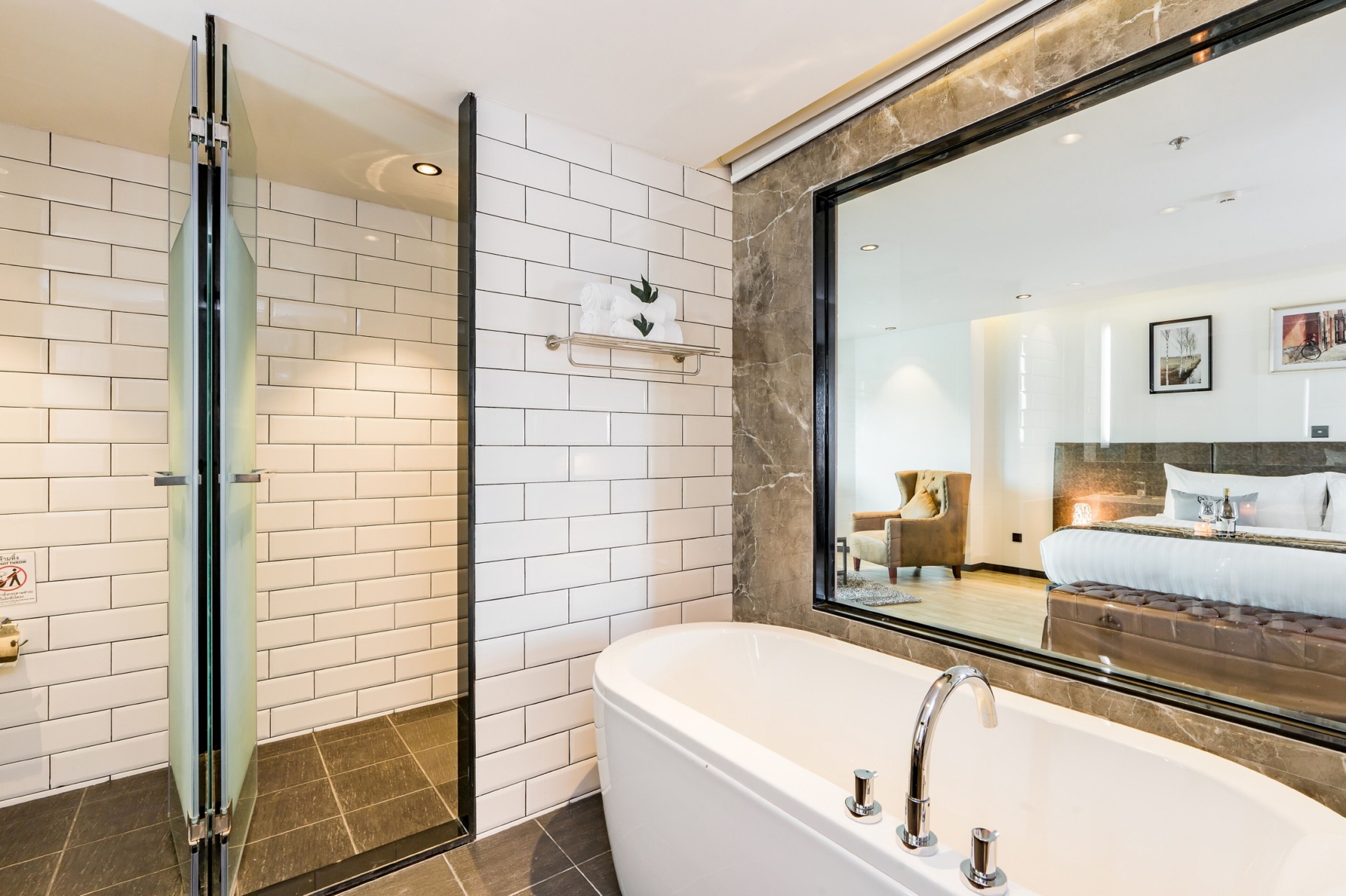 Un baño moderno con cabina de ducha de vidrio, una bañera independiente y un espejo grande que refleja la habitación.