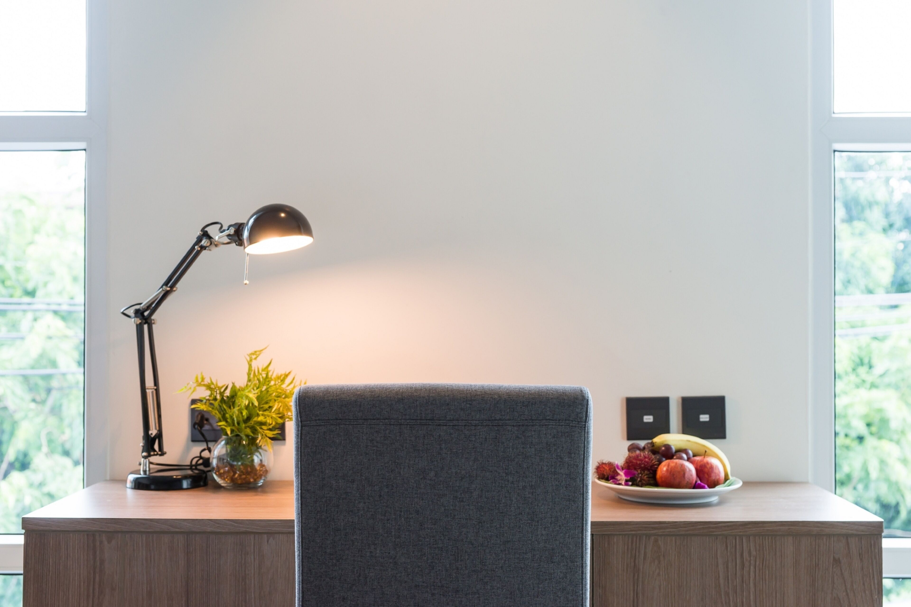 A desk with a lamp, a plant, and a fruit plate.