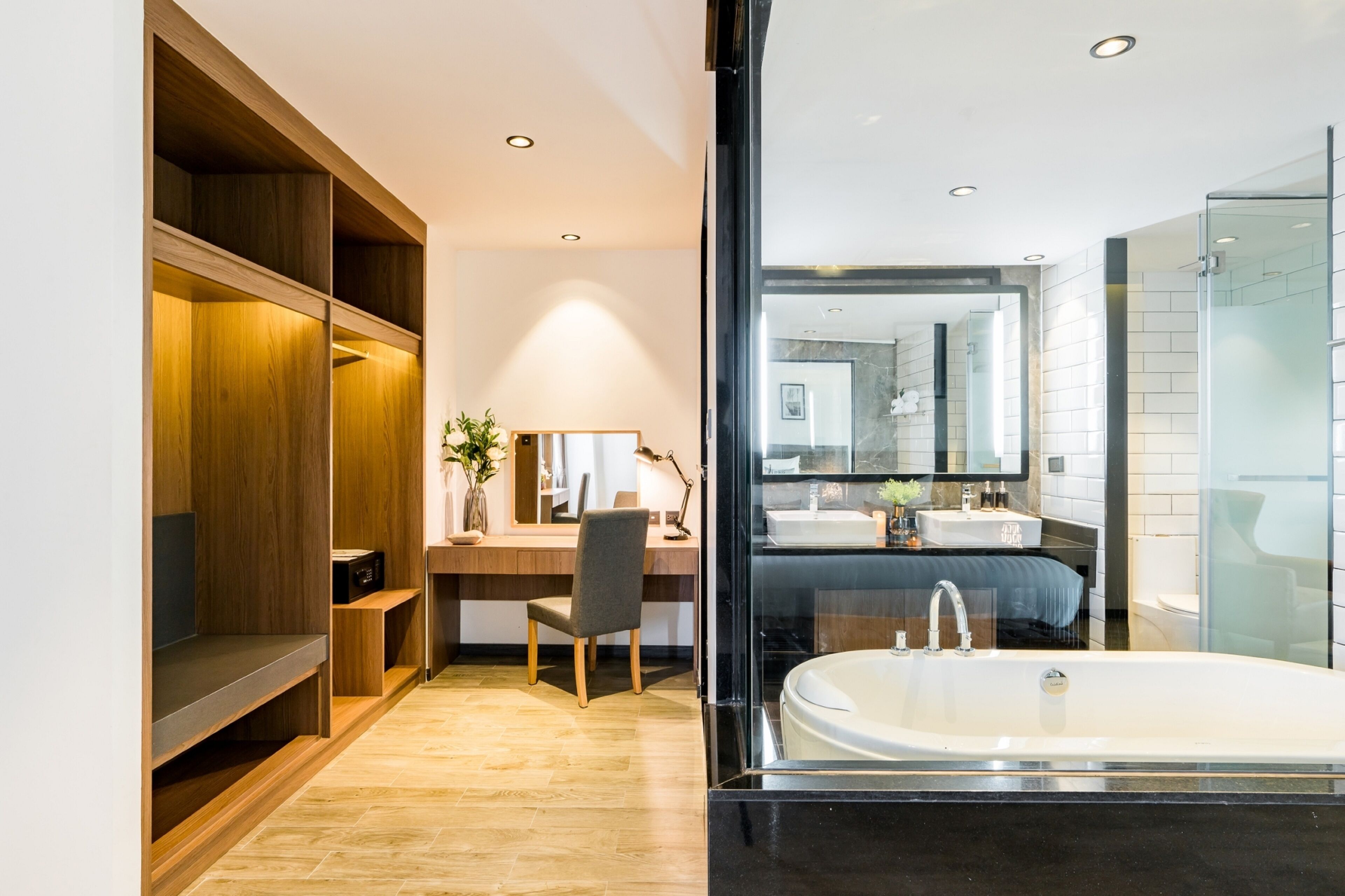 A modern bathroom with a large mirror, a bathtub, and a wooden vanity.