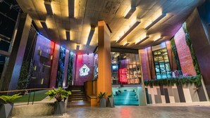 Eine moderne Hotellobby mit einer Treppe zu den oberen Etagen, einer Rezeption und Blick auf den Parkplatz.