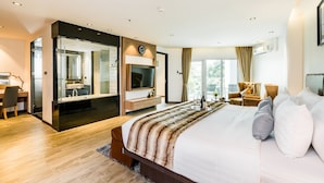 Ein modernes Hotelzimmer mit einem großen Bett, einem Fernseher, einem Schreibtisch und einem Badezimmer mit Glasdusche.