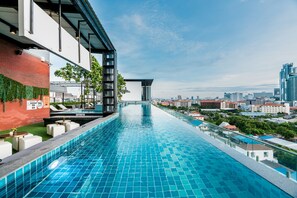 A long, narrow infinity pool with a cityscape view, modern architecture, and outdoor seating. - SureStay Plus by Best Western T Pattaya (Pattaya)