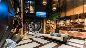Eine moderne Lobby mit einem geometrischen Bodenmuster, einem Empfangstresen und einem Fernseher, der eine Stadtansicht zeigt.