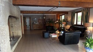 Un vaste espace de vie doté d’une cheminée, de canapés en cuir, d’une table basse et d’un coin repas situé à l’arrière-plan.