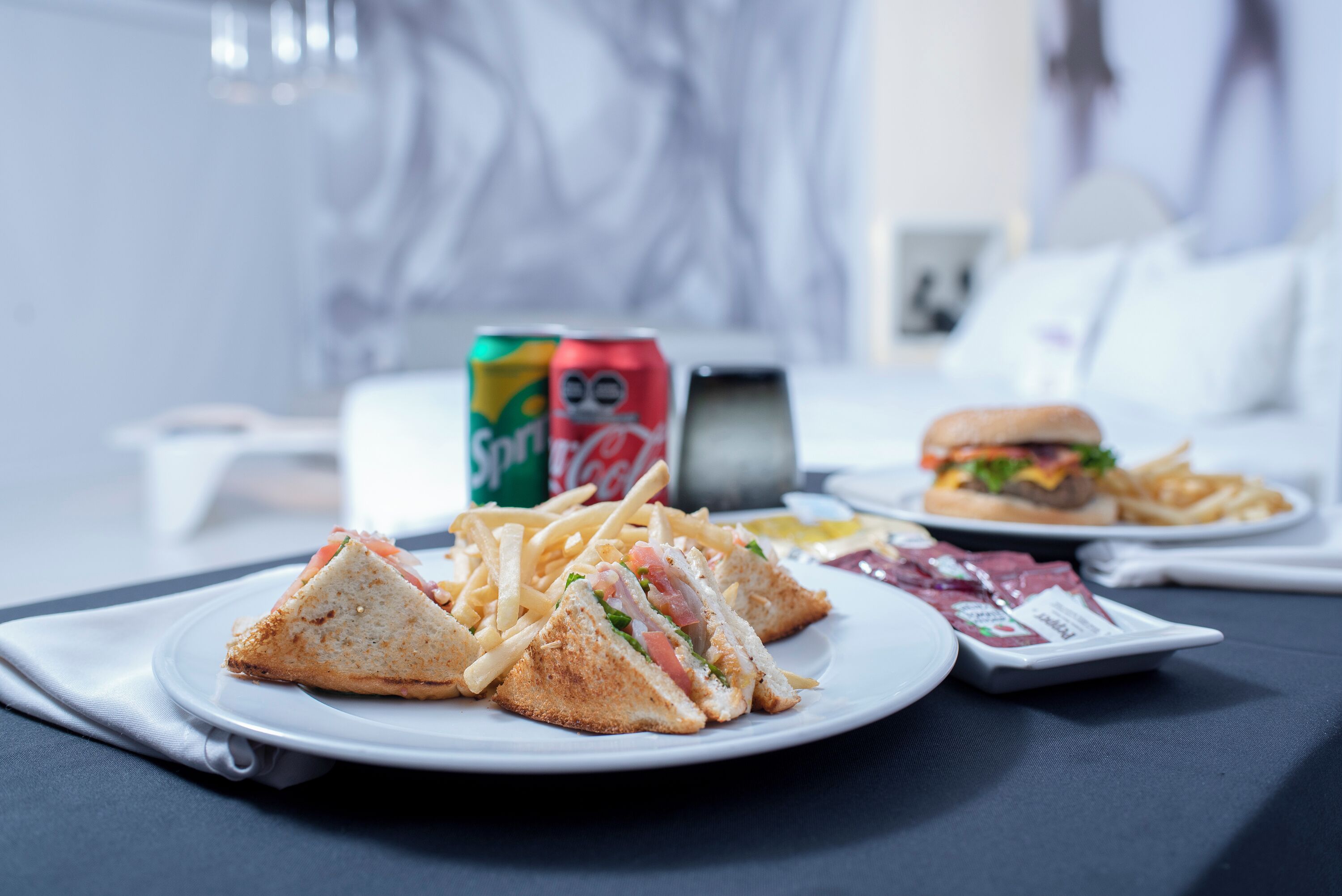 En tallerken med en sandwich, pommes frites og drikke på et bord.