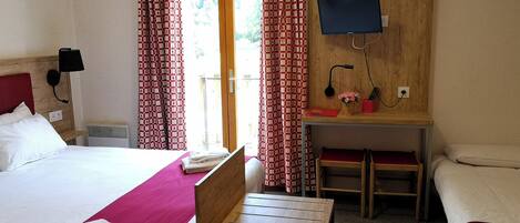 A hotel room with a bed, a desk, a chair, a TV, and a window with curtains.