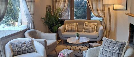 Una sala de estar acogedora con un sofá, dos sillones, una mesita de centro y una chimenea.