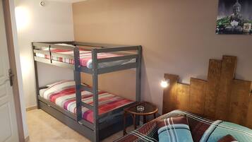 Habitación con literas, una mesita pequeña y un cuadro en la pared.