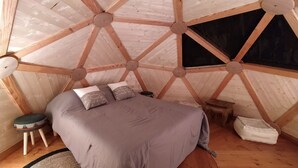 A cozy, circular wooden tent with a bed, pillows, and a small stool. - La Maison de Tari (Vitrac)