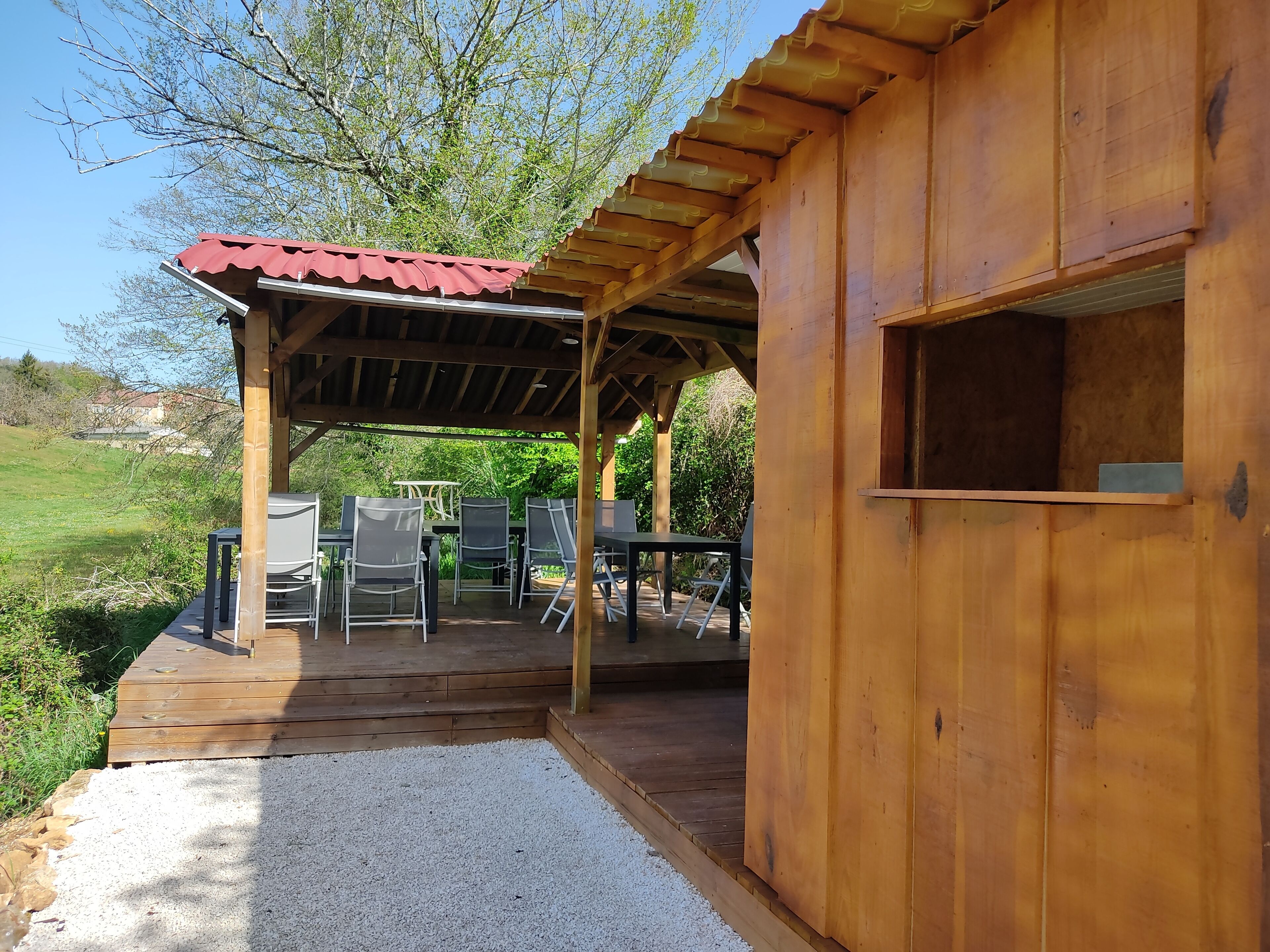 Una cabaña de madera con un porche cubierto, mobiliario exterior y un sendero de grava.