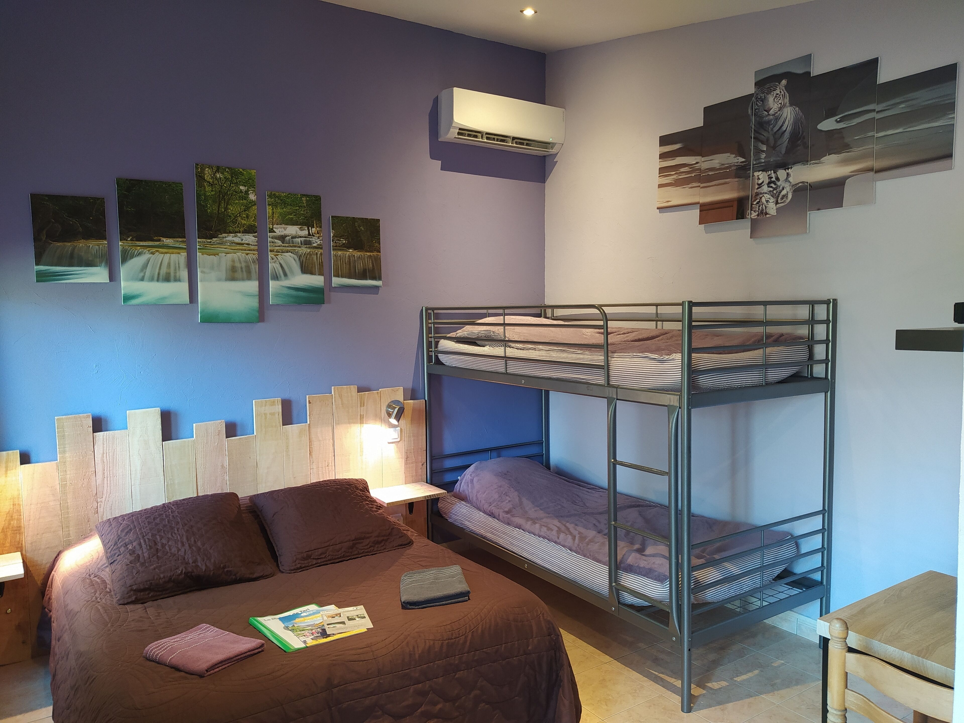 A room with a bunk bed, a wooden headboard, a wall-mounted air conditioner, and framed pictures.