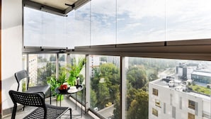 A balcony with a table and chairs, a potted plant, and a city view. - Good Time Apartment (Warsaw)