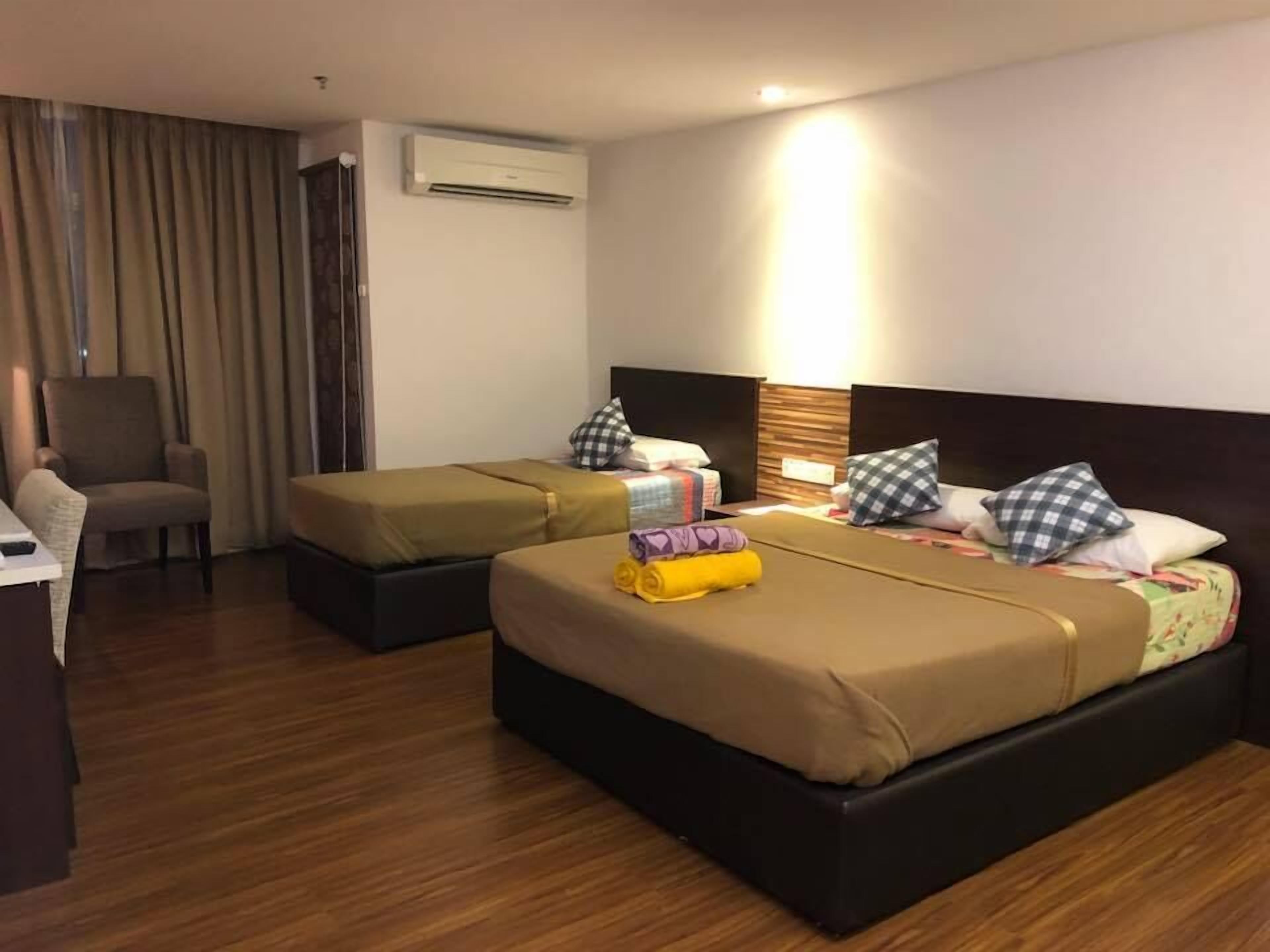 A hotel room with two beds, a desk, a chair, and an air conditioning unit.