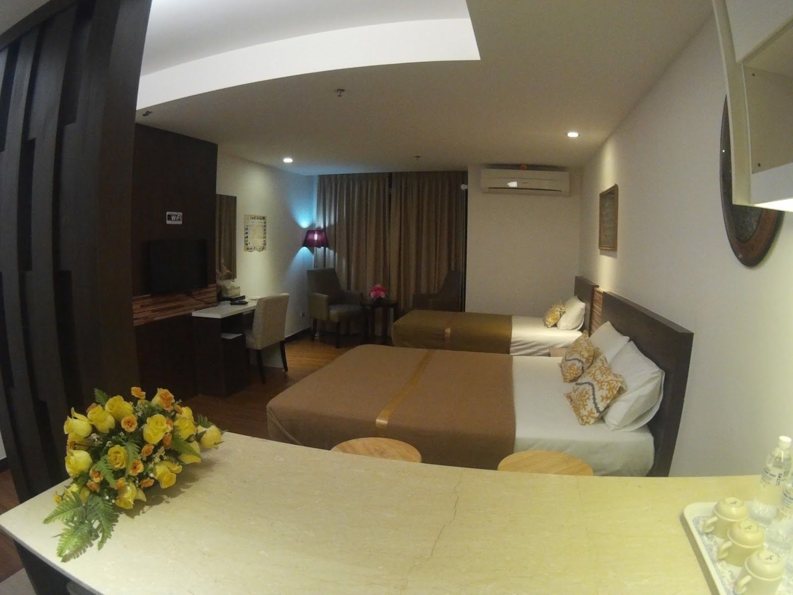 A hotel room with a bed, a desk, a chair, a TV, and a bathroom.