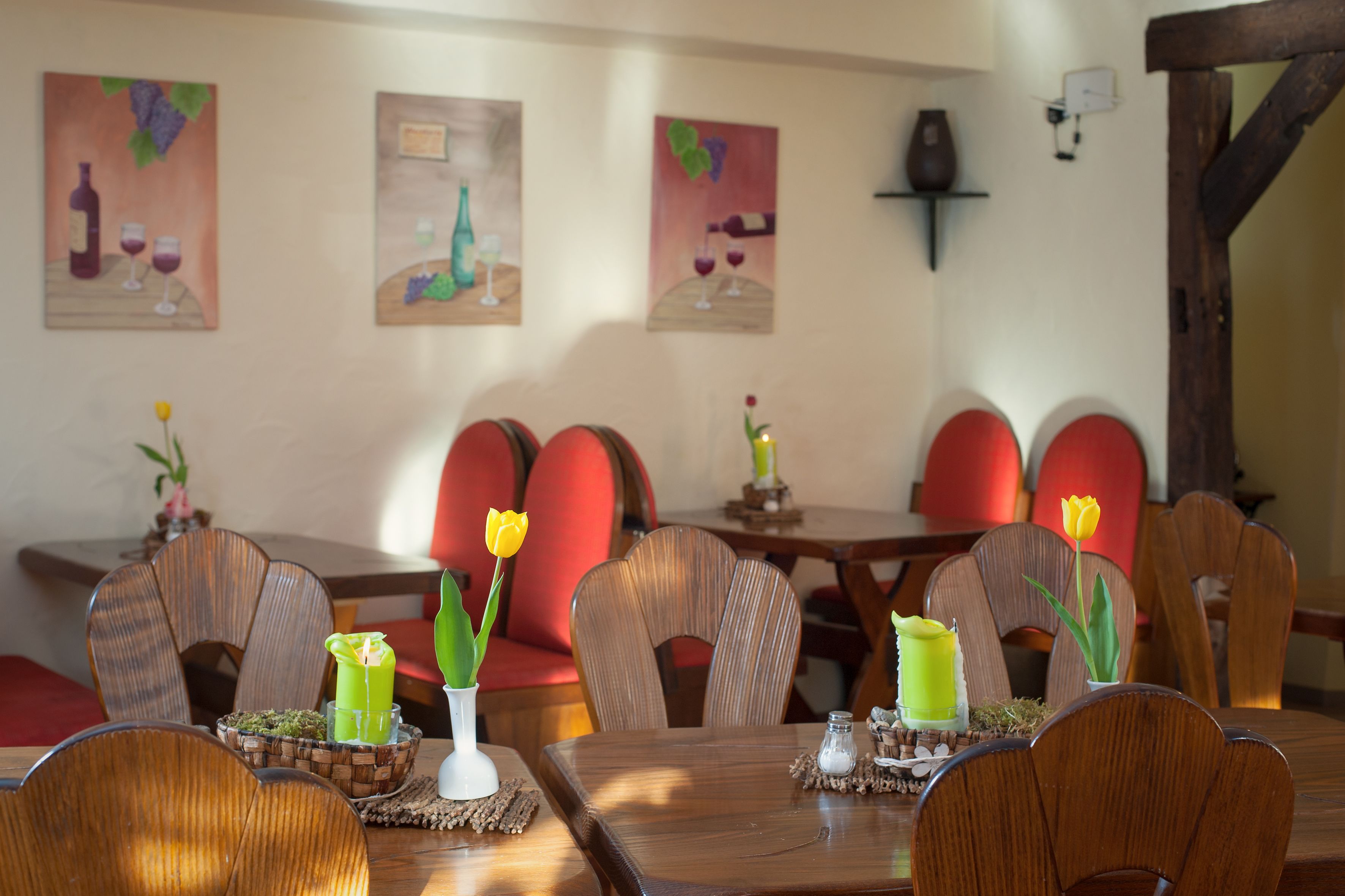 A dining area with wooden tables and chairs, decorated with candles and flowers.