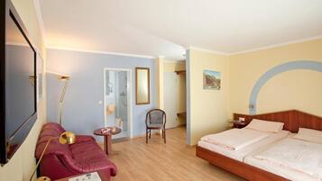 Een hotelkamer met een bed, een bank, een stoel, een klein tafeltje en een spiegel.