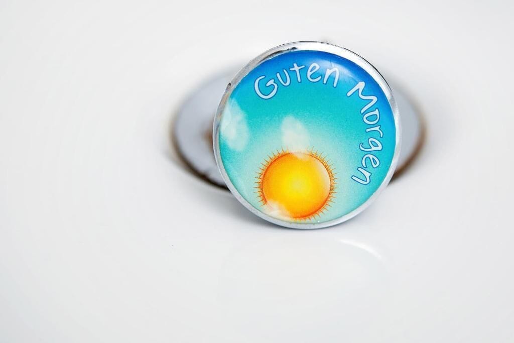 Un anello con un disegno a forma di sole e il testo 'Guten Morgen'.