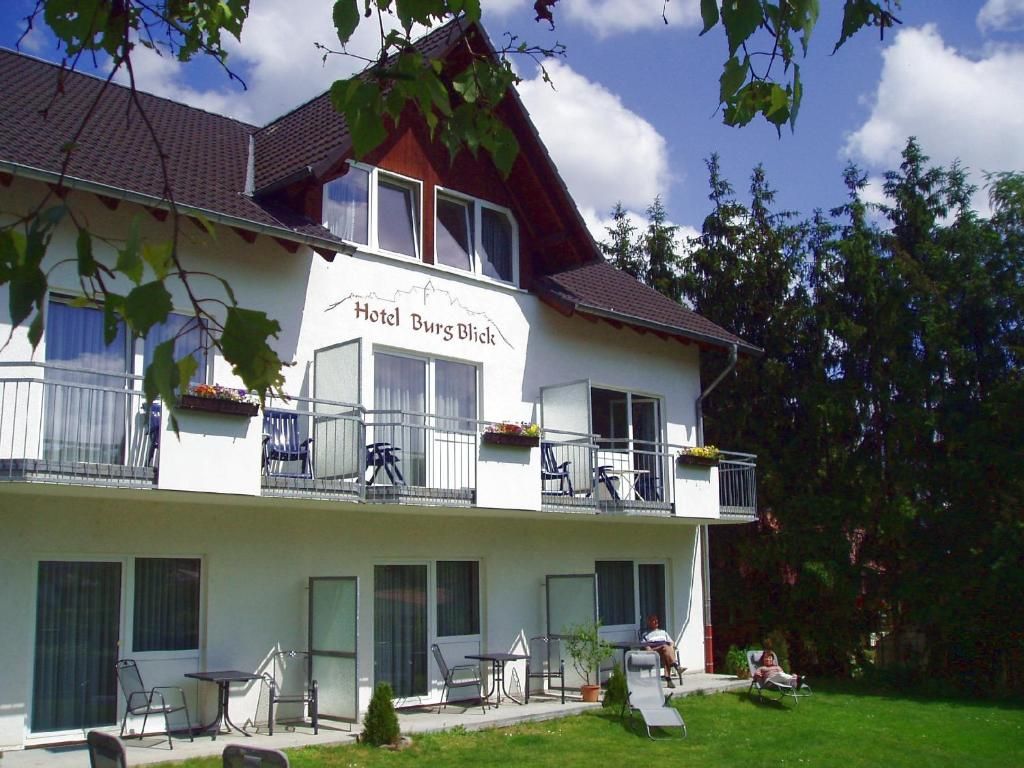 A two-story hotel with balconies, outdoor seating, and a sign reading 'Hotel Burg Blick'.
