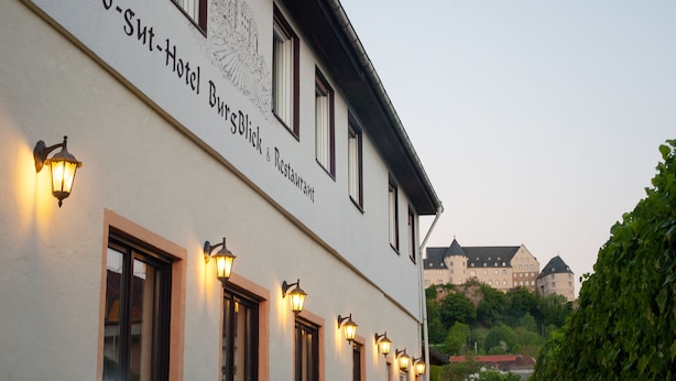 Un edificio de hotel con el nombre "Land-Sut-Hotel Biersblick & Restaurant" y un castillo al fondo.
