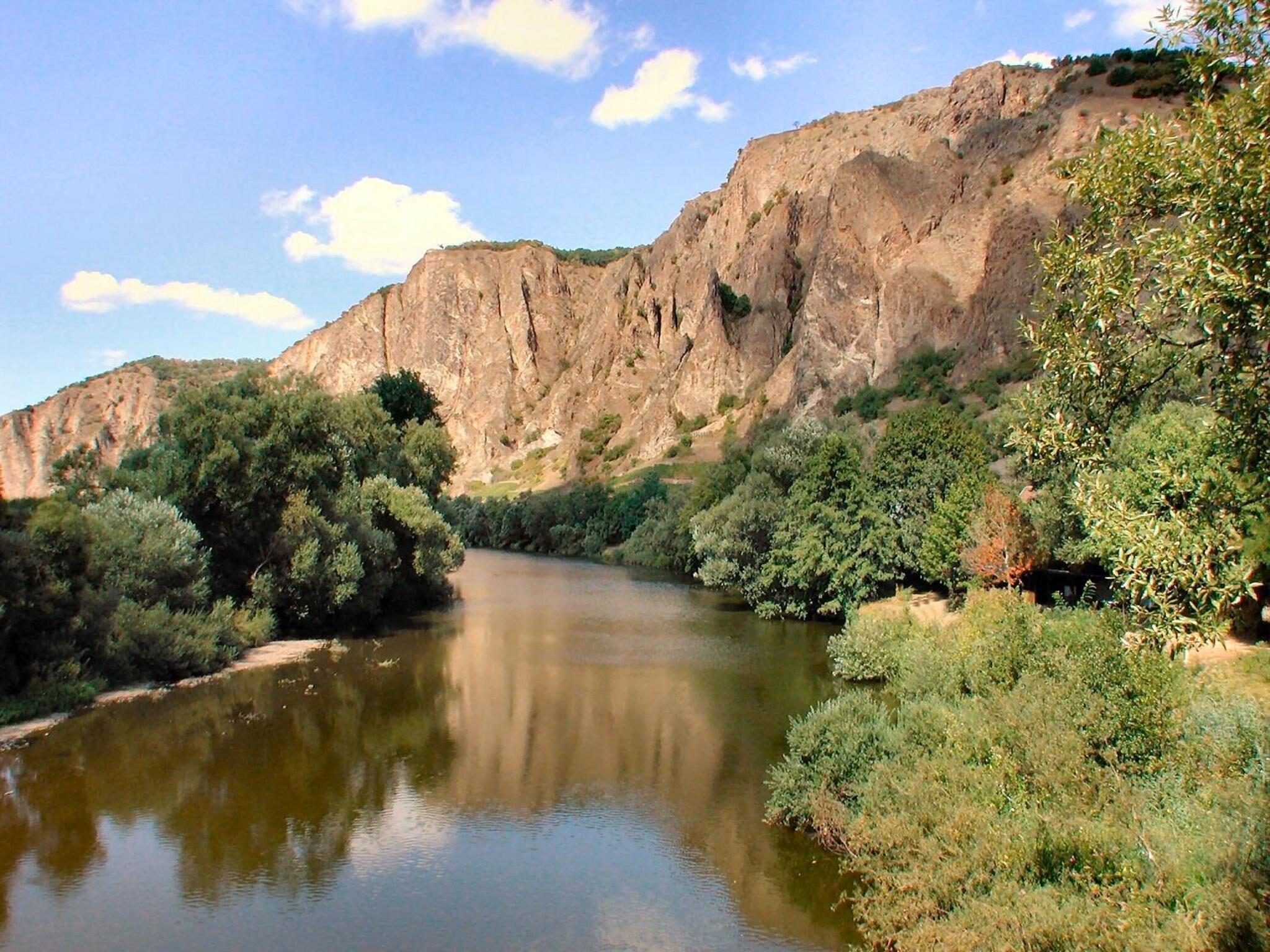 Ein Fluss fließt durch eine Schlucht mit steilen Felswänden und dichter Vegetation an beiden Ufern.