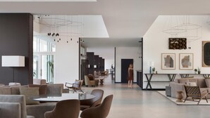 Un vaste espace de vie moderne comprenant une table à manger, des canapés et un escalier menant à un niveau supérieur.