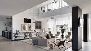 Un salon spacieux doté d’un haut plafond, de meubles modernes et d’une grande fenêtre laissant entrer la lumière naturelle.