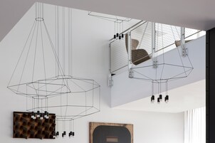 Un interno moderno con lampade pendenti geometriche, un'opera d'arte dalla texture particolare e un quadro incorniciato.