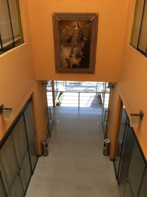 A corridor with a framed painting on the wall, glass doors, and trash bins. - Apart Hotel Incamin (Arequipa)