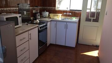 A kitchen with a microwave, stove, sink, and cabinets.