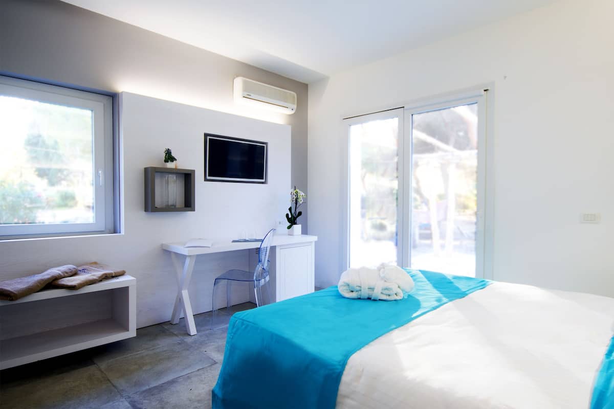 Una camera da letto moderna con un letto, una scrivania e una sedia. Una finestra offre luce naturale e vista sull'esterno.