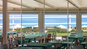 An outdoor dining area with tables set for guests, overlooking a beach and the ocean. - BV Kalafiorita Resort (Zambrone)